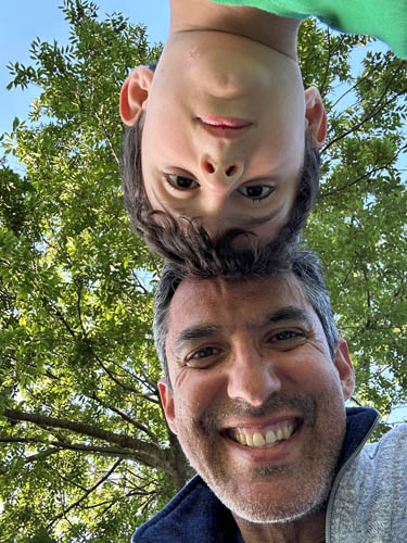 Man and boy, heads touching, with a tree in the background