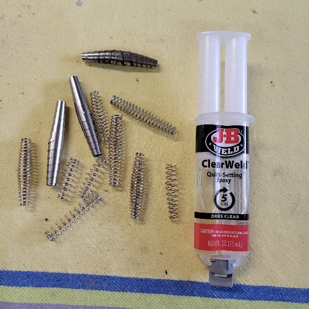 A tube of glue next to several metal springs.