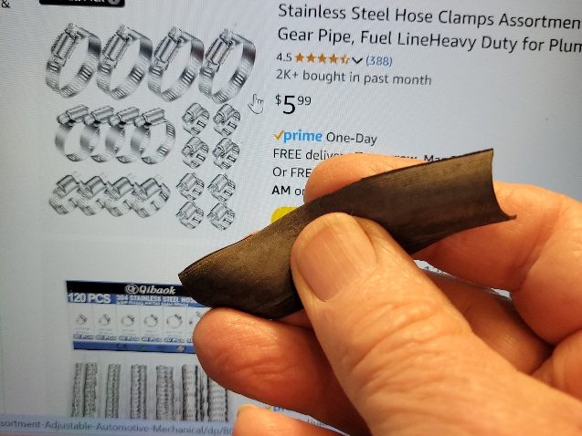 A hand holding a piece of bike inner tube. In the background is an Amazon webpage, Stainless Steel Hose Clamps Assortment for $5.99.