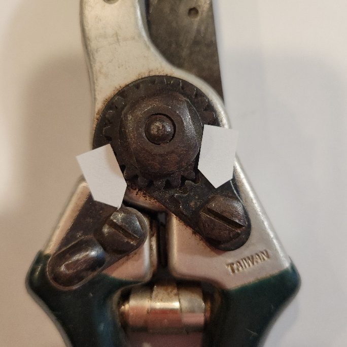 A close-up of a pruner. Arrows point to the two screws.