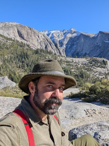 A man wearing green in the mountains.